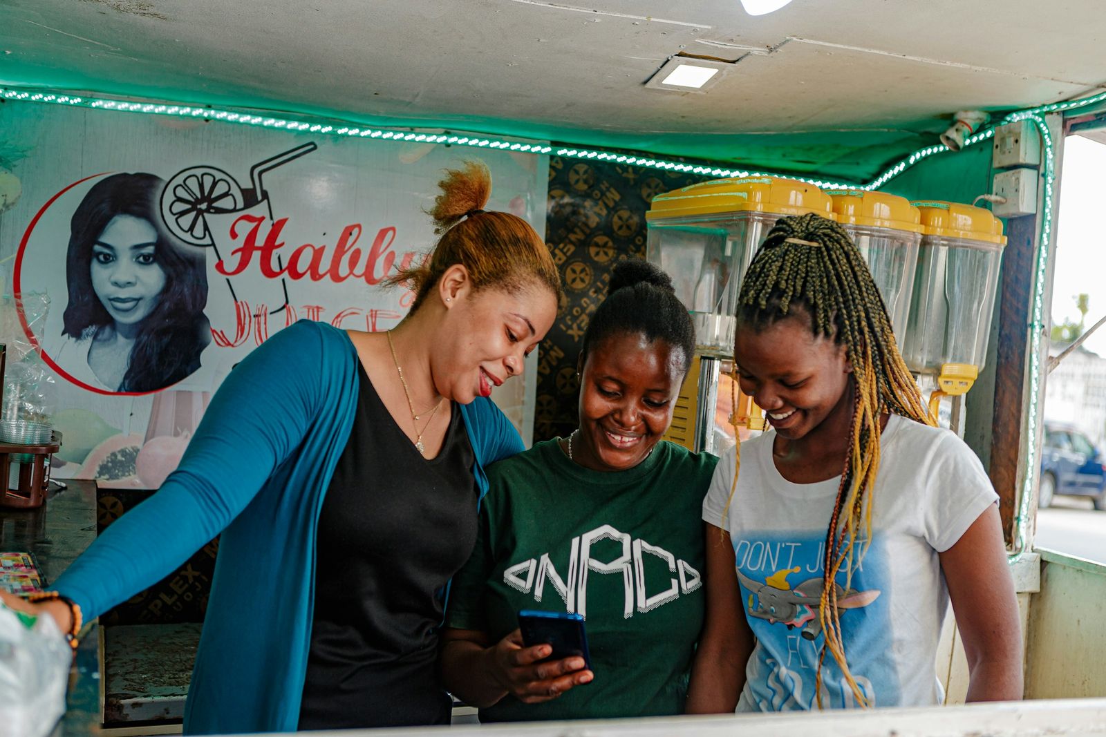 Three Black women laughing together while looking at a phone